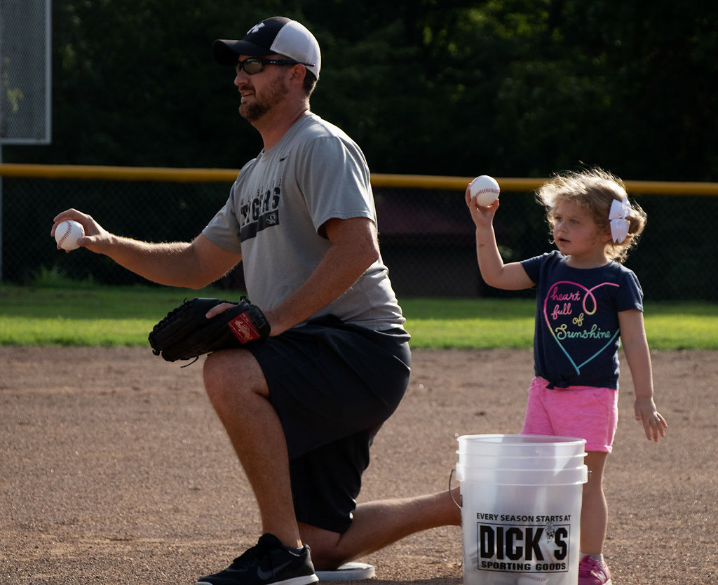 Nate Alexander and his daughter, Emery, 2, throw warm up pitches for son Rhett, 6, before his practice